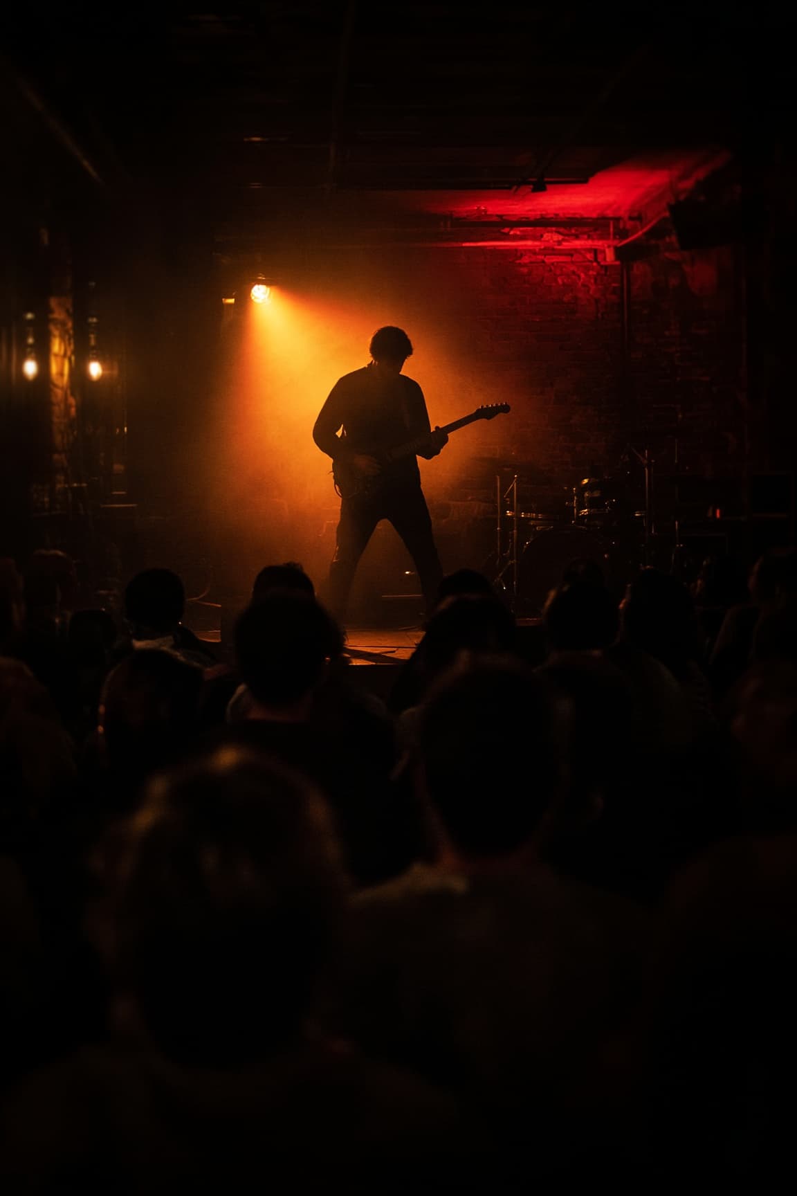 Guitarist in silhouette under stage lights