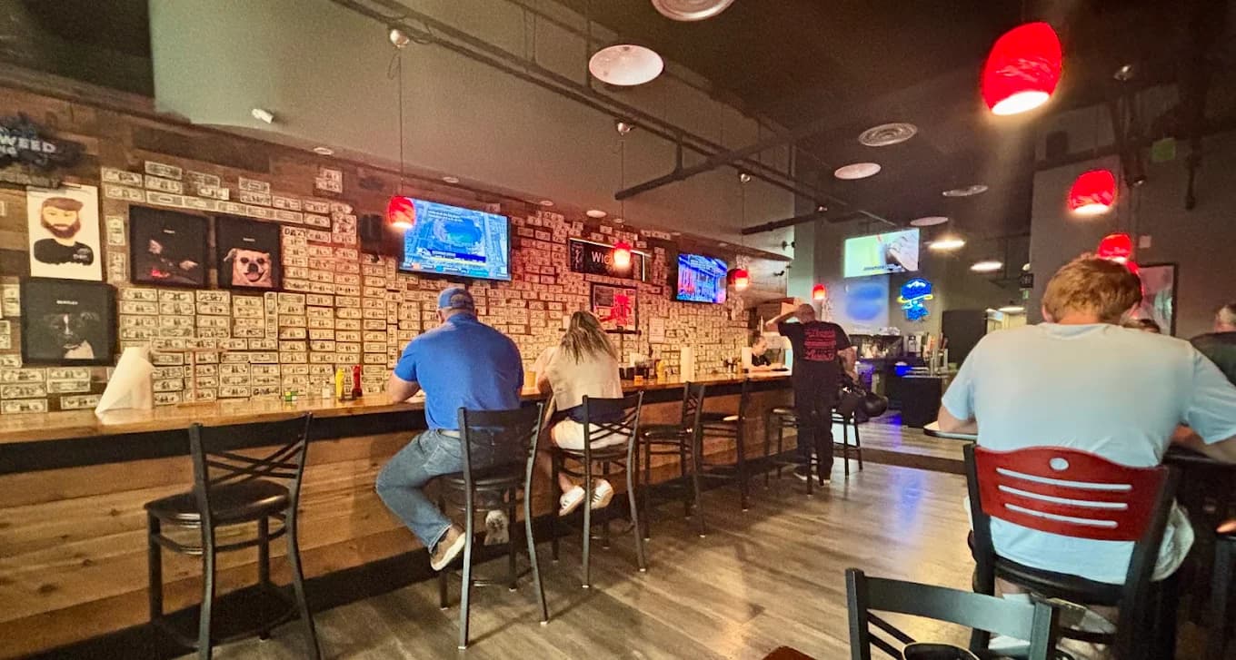 The Wicked Pub bar with the dollar-covered wall, TVs and red pendant lights